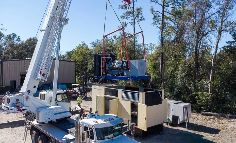 Diesel generator being installed at an industrial facility by a crew of technicians.