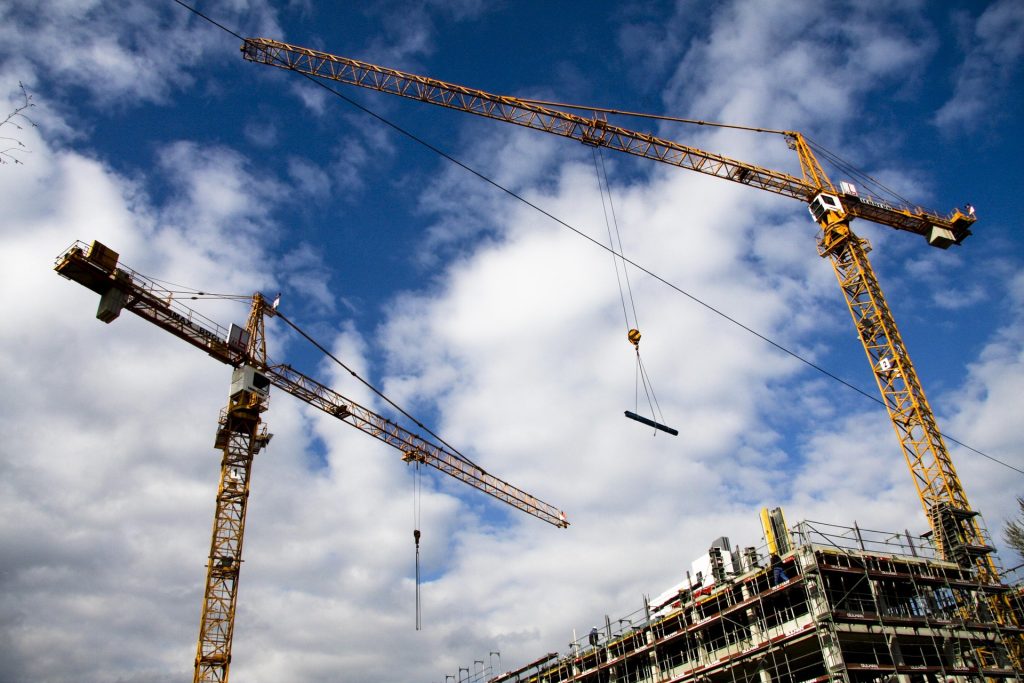 Two large tower cranes operating on a multi story building construction site